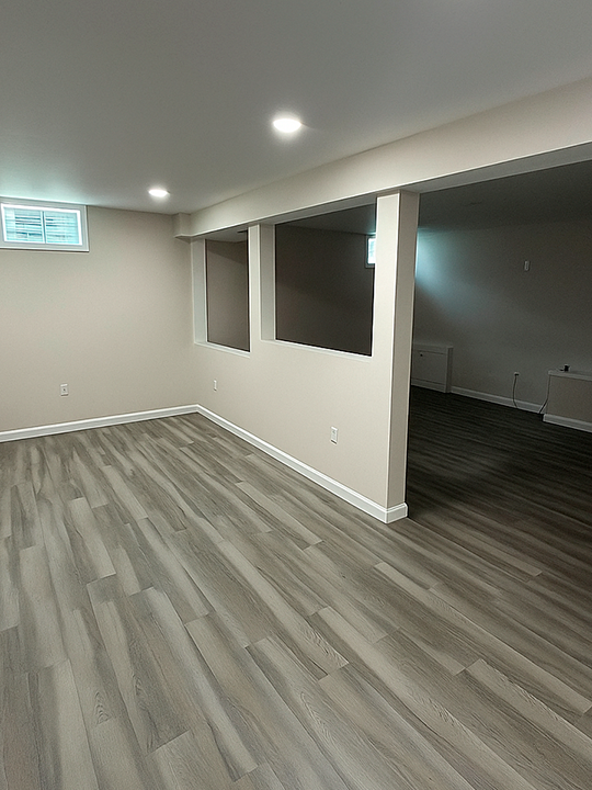 Finished basement with vinyl plank flooring and recessed lighting