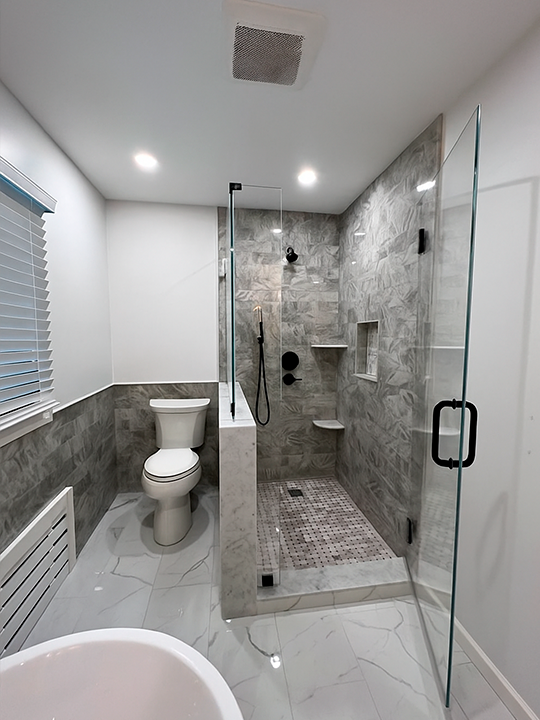 Contemporary bathroom renovation with glass shower and dark tile accents