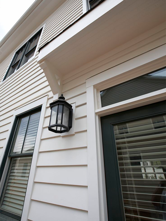 Close-up of new siding panels with exterior wall light fixture